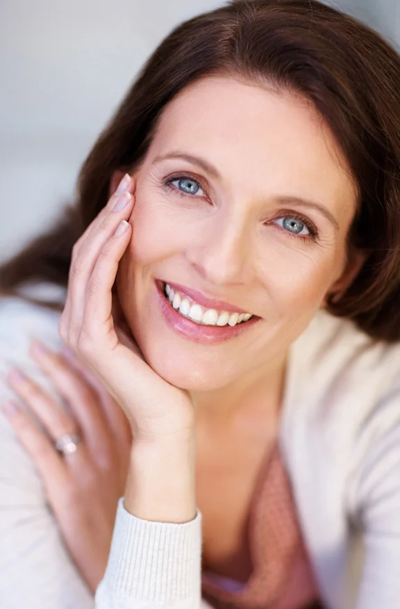 Woman smiling with her hand on her face - the benefits of Co2 Skin Resurfacing in Farmington Hills, MI