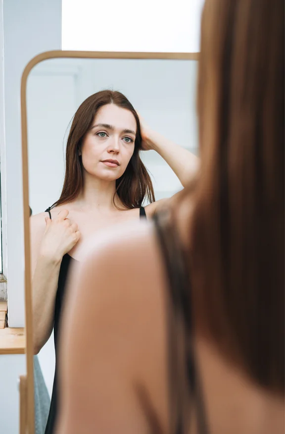 Woman looking in mirror - Hair Restoration - Revive Medical Spa