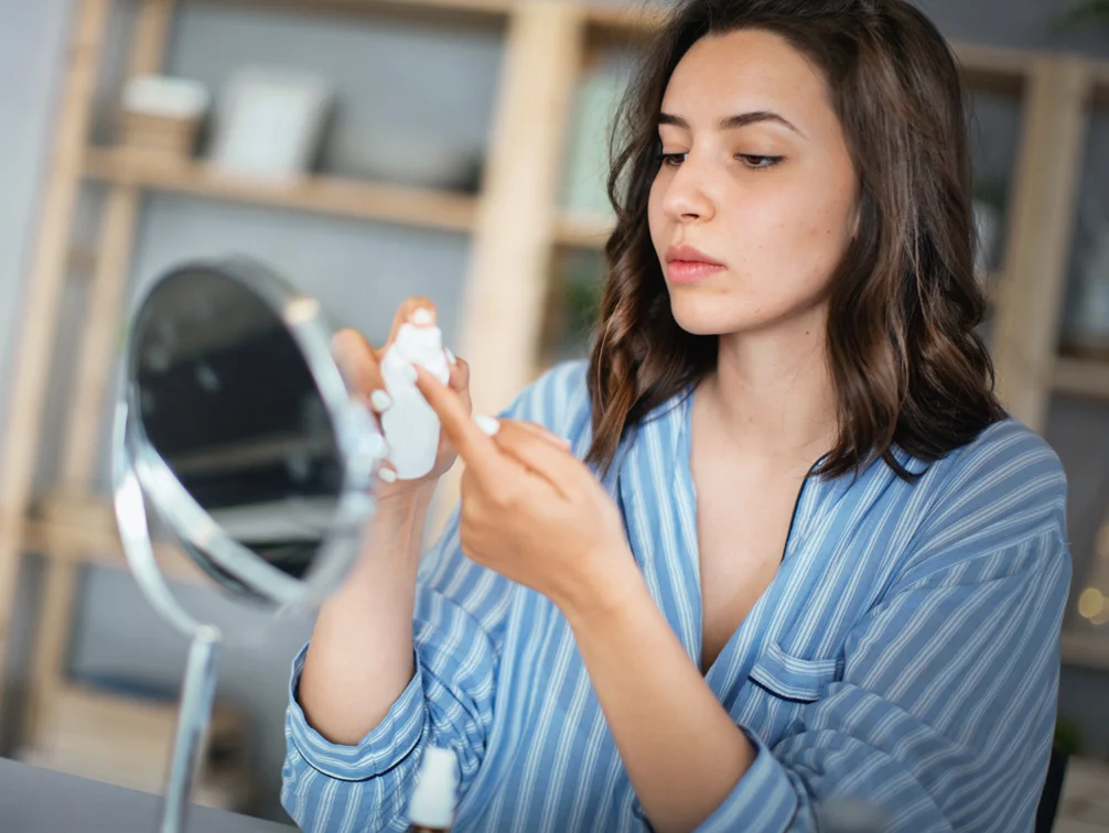 Woman applying serum to finger- Acne Scar Reduction