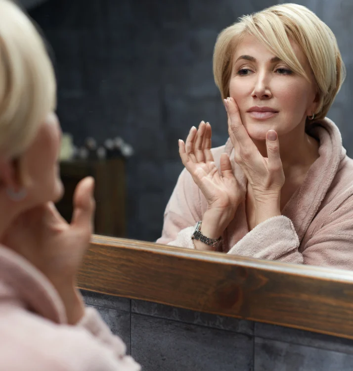 Middle aged woman admiring her smooth skin in a mirror