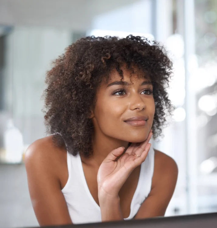 African American woman looking at the mirror - Chemical Peels